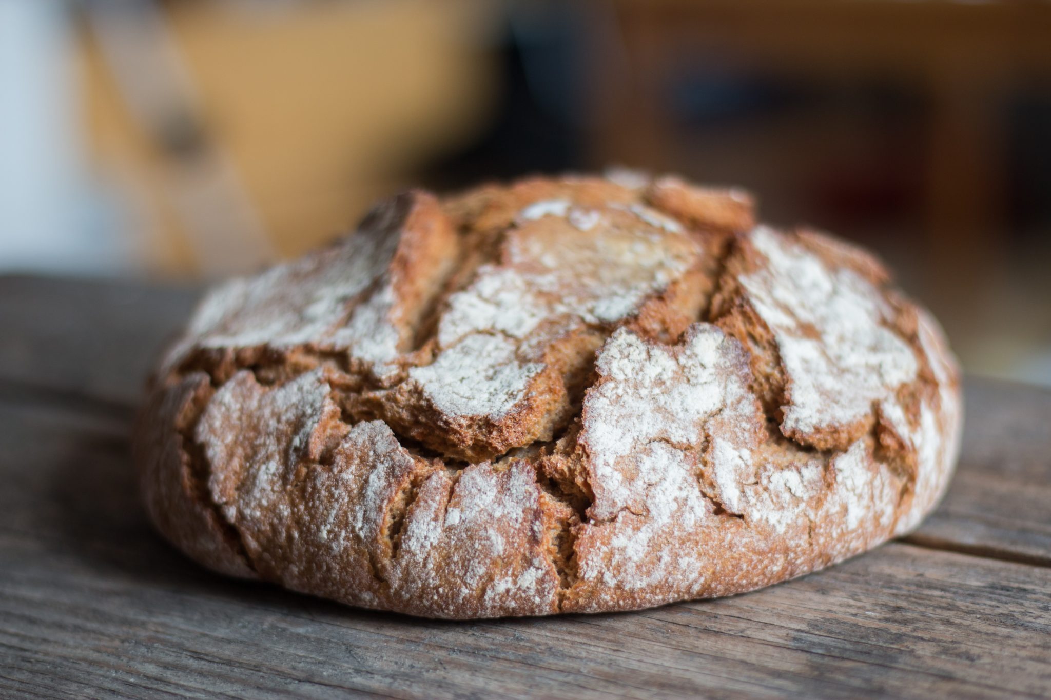 Fresh dark bread on rustic wooden cutting board, outdoors