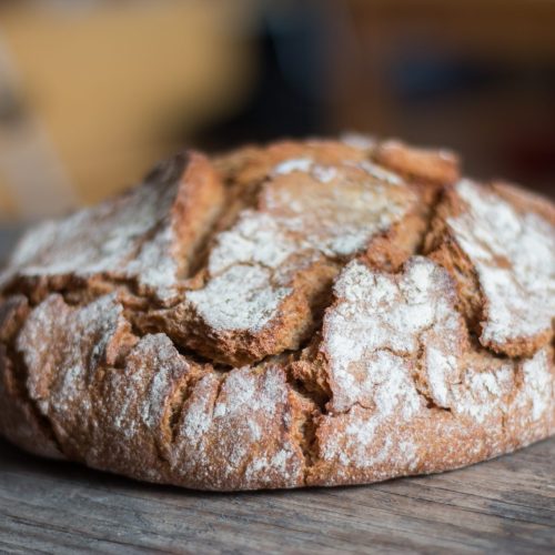 Fresh dark bread in slices. Rustic wooden cutting board